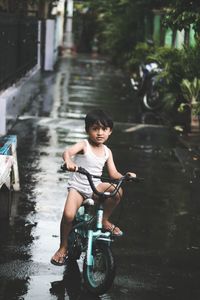 Boy riding bicycle on wet street