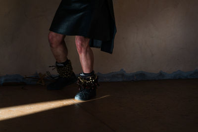 Low section of man wearing ghungroo while dancing against wall