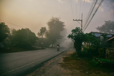 Man riding motorcycle on road in city during fogy weather