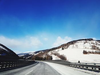 Road by mountain against sky during winter