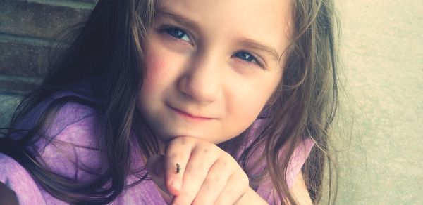 Close-up portrait of cute girl with insect