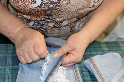 Midsection of woman stitching fabric at table