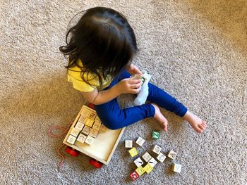 High angle view of girl playing with toy blocks on carpet at home