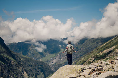 Rear view of man standing on mountain against sky