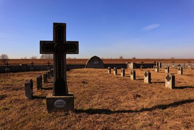 Cross on cemetery against clear blue sky