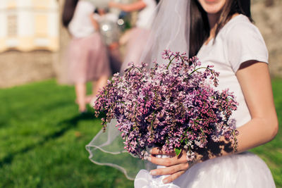 Midsection of woman holding pink flowering plant