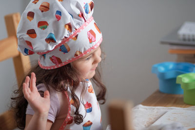 A young girl is playing chef at the kitchen table.