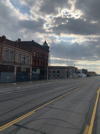 Road by buildings against sky in city