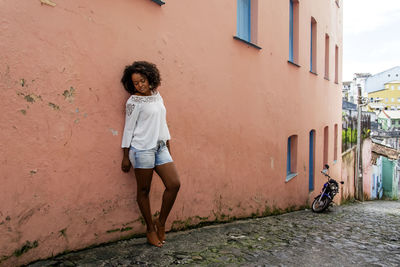 Rear view of young woman standing against wall