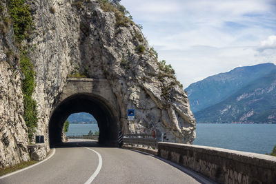 Bridge over road by mountain against sky