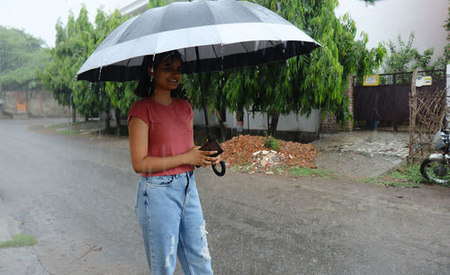 Portrait of woman with umbrella standing in rain