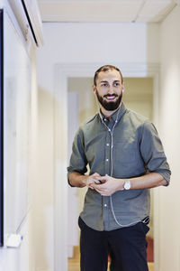 Happy businessman listening music through headphones in office