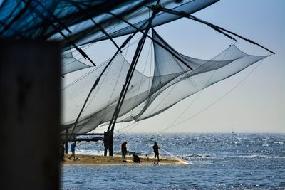 Fisherman fishing in sea against sky