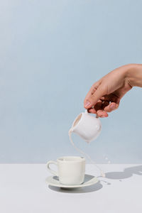 Close-up of hand pouring coffee cup on table