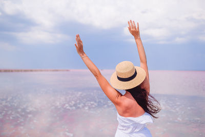 Rear view of woman wearing hat standing at beach