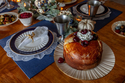 Panettone bread with cherries and whipped cream on a holiday table at christmas.