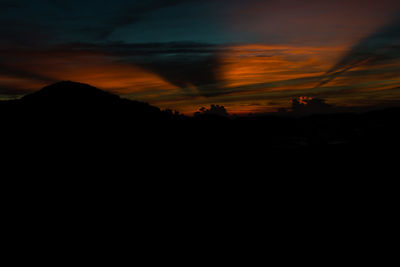 Silhouette landscape against dramatic sky during sunset