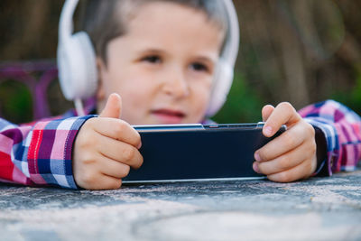 Cute boy listening music while using mobile phone outdoors