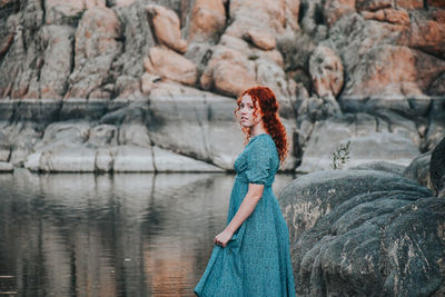 Woman with redhead standing against lake and rock formations