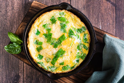 Omelet with spinach and cheese in a pan on the table. ketogenic diet. top view. closeup