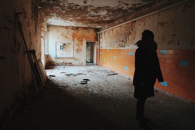 Rear view of woman standing in abandoned building