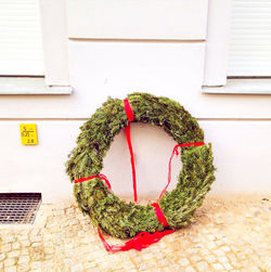 Wreath on footpath against wall