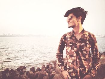 Young man looking at sea against sky