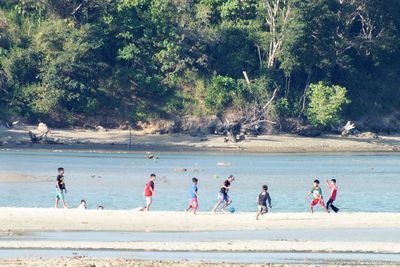 Group of boys playing soccer by lake in forest