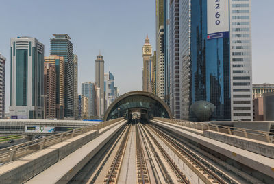 Railroad tracks amidst buildings in city against sky