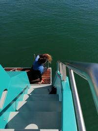 High angle view of woman sitting by ladder of boat on sea