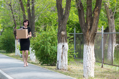 A frustrated fired woman with box in her hands walks through the city.