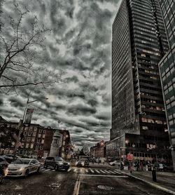 Road by buildings in city against sky during rainy season