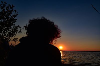 Rear view of silhouette woman looking at sunset