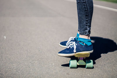 Low section of woman skateboarding on road