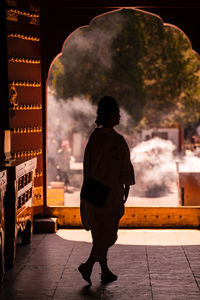 Rear view of man walking in illuminated city at night