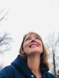 Low angle view of smiling woman against sky in winter