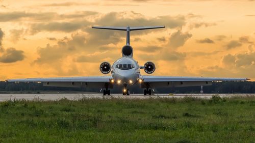 Airplane on field against sky during sunset