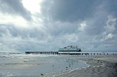 View of calm beach against cloudy sky