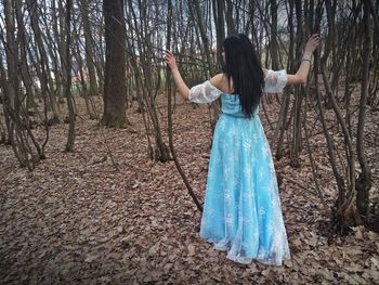 Woman wearing blue dress while standing in forest