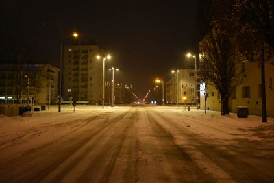 Street by illuminated buildings in city at night