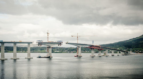 Boats in river against cloudy sky