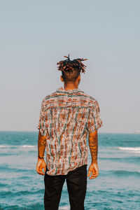 Rear view of man standing on beach against clear sky