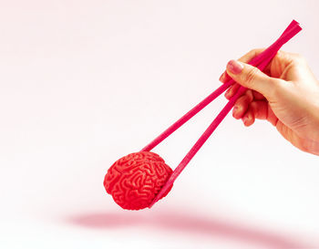 Close-up of hand holding pencil against white background