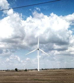 Wind turbines on field against sky