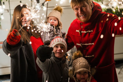 Portrait of cheerful family members holding sparklers