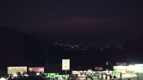 Crowd on illuminated city against sky at night