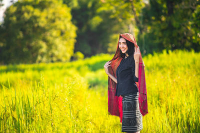 Portrait of smiling young woman standing on field