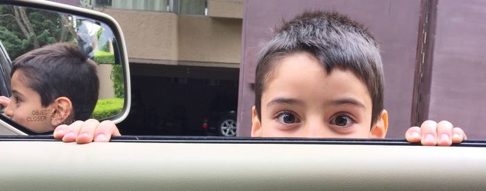 Portrait of boy holding car door