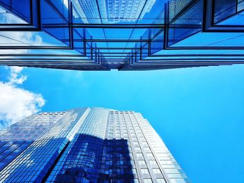 Low angle view of modern glass building against blue sky