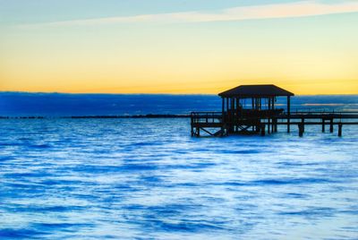 Pier on sea at sunset